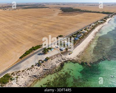 Vista aerea di terreni agricoli dietro una rotonda costiera e di una piccola comunità sopra la spiaggia di Point Turton sulla penisola di Yorke nell'Australia meridionale. Foto Stock