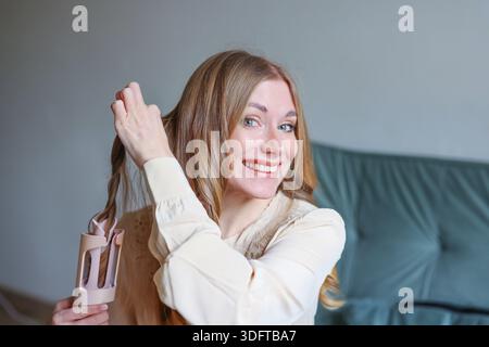 Concetto di bellezza femminile positivo con la donna che acconcia i capelli e che sembra sicura e felice Foto Stock