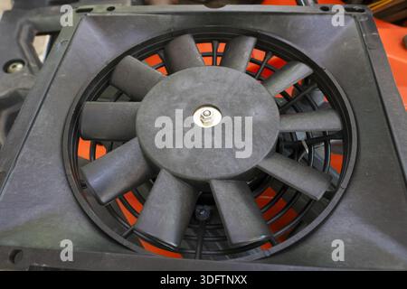 Ventola radiatore nera polverosa con pale e telaio per la sostituzione dei componenti del motore del sistema di raffreddamento del veicolo che mostra una consistenza usurata e industriale Foto Stock