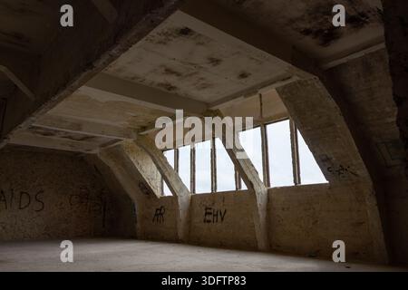 All'interno di un attico spogliato con finestre lucernari e dettagli costruttivi. Alcuni graffiti sulle vecchie pareti di cemento Foto Stock