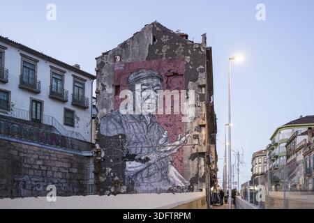 Porto, Portogallo - 26 novembre 2017: Veduta di un colossale murale monocromatico di un uomo con uno sfondo rosso adorna un edificio intempestivo, agains giustapposte Foto Stock