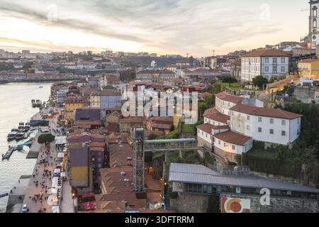 Porto, Portogallo - 26 novembre 2017: Vista dei colorati edifici di Ribeira che scendono fino al fiume Douro sotto un cielo soffice e luminoso, con il Dom Luí Foto Stock