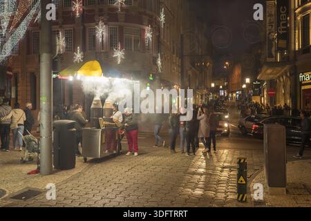 Porto, Portogallo - 26 novembre 2017: Vista di una vivace scena di strada con lo stand fumé di un venditore di castagne illuminato da luci festose vicino all'iconico Foto Stock