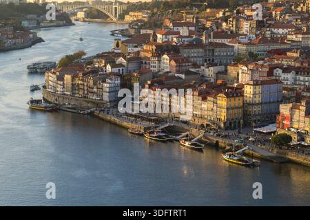 Porto, Portogallo - 26 novembre 2017: Veduta del fiume Douro che riflette la luce dorata del sole che tramonta, illuminando il colore del quartiere di Ribeira Foto Stock