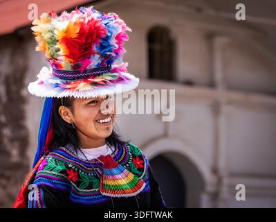 Vista di una donna sorridente in un abbigliamento tradizionale, il suo vibrante cappello piuma una raffica di colori sullo sfondo pallido, l'isola di Taquile, Perù. Foto Stock