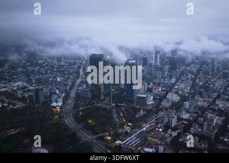 Veduta aerea dei grattacieli che penetrano nella nebbia, gettando lunghe ombre sulle vivaci strade del Paseo de la Reforma, città del Messico, Messico. Foto Stock