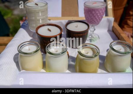 Assortimento di candele aromatiche fatte a mano in eleganti vasetti di vetro e argilla. Concetto di mostre di artigianato, accogliente fragranza casalinga e interni minimalisti Foto Stock