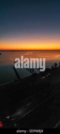 Vista aerea del lungo molo che si estende nelle tranquille acque sotto un vibrante cielo al tramonto, Sebastian, Florida, Stati Uniti. Foto Stock