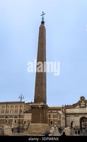 Un'alta colonna corinzia sormontata da una statua di bronzo si erge contro un cielo limpido in una storica piazza romana Foto Stock