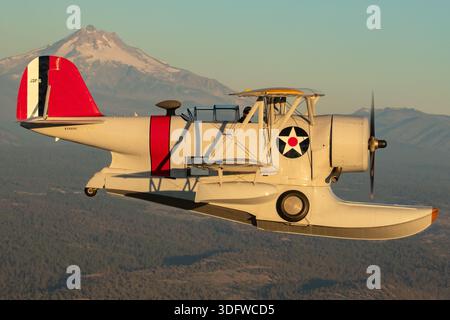 L'immagine mostra un biplano anfibio Grumman J-2F-6 Duck in volo, visto da vicino da una prospettiva aria-aria con il pilota visibile nella cabina di pilotaggio aperta. Questo aeromobile ha la registrazione civile N3960C e il numero di costruzione 33559. Il J-2F-6 Duck fu costruito dalla Grumman come biplano monomotore a due vani con carrello di atterraggio retrattile per le operazioni di terra e di acqua. È alimentato da un motore radiale Wright R-1820 Cyclone a nove cilindri raffreddato ad aria. Questo Warbird restaurato è gestito come parte della Erickson Airshow Collection e rappresenta una configurazione Duck di produzione tardiva. Foto Stock