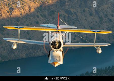 L'immagine mostra un biplano anfibio Grumman J-2F-6 Duck in volo, visto da vicino da una prospettiva aria-aria con il pilota visibile nella cabina di pilotaggio aperta. Questo aeromobile ha la registrazione civile N3960C e il numero di costruzione 33559. Il J-2F-6 Duck fu costruito dalla Grumman come biplano monomotore a due vani con carrello di atterraggio retrattile per le operazioni di terra e di acqua. È alimentato da un motore radiale Wright R-1820 Cyclone a nove cilindri raffreddato ad aria. Questo Warbird restaurato è gestito come parte della Erickson Airshow Collection e rappresenta una configurazione Duck di produzione tardiva. Foto Stock