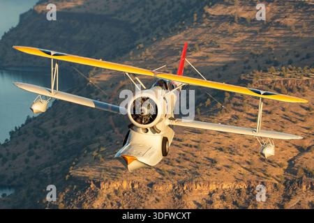 L'immagine mostra un biplano anfibio Grumman J-2F-6 Duck in volo, visto da vicino da una prospettiva aria-aria con il pilota visibile nella cabina di pilotaggio aperta. Questo aeromobile ha la registrazione civile N3960C e il numero di costruzione 33559. Il J-2F-6 Duck fu costruito dalla Grumman come biplano monomotore a due vani con carrello di atterraggio retrattile per le operazioni di terra e di acqua. È alimentato da un motore radiale Wright R-1820 Cyclone a nove cilindri raffreddato ad aria. Questo Warbird restaurato è gestito come parte della Erickson Airshow Collection e rappresenta una configurazione Duck di produzione tardiva. Foto Stock