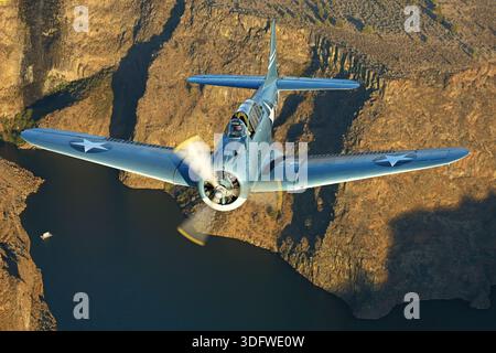 Il Douglas SBD Dauntless con registrazione NX5254L, numero di serie 2350, è un bombardiere in picchiata biposto, monomotore della United States Navy della seconda guerra mondiale, ora utilizzato come un uccello da guerra civile. Questa variante di velivolo è stata progettata per lo scouting e il bombardamento in picchiata basato su portaerei ed è alimentata da un motore radiale Wright R‑1820‑60 Cyclone raffreddato ad aria con una potenza di circa 1.200 cavalli. È dotato di freni fissi, mitragliatrici a fuoco anteriore e posteriore ed è mostrato qui in una vista ravvicinata del pilota durante un volo aria-aria all'Erickson Airshow Collection 2025. Foto Stock