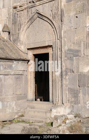 Tatev, Armenia - 8 gennaio 2026: Porta in pietra scolpita del monastero di Tatev con struttura ad arco, blocchi calcarei intemprati, gradini poco profondi Foto Stock