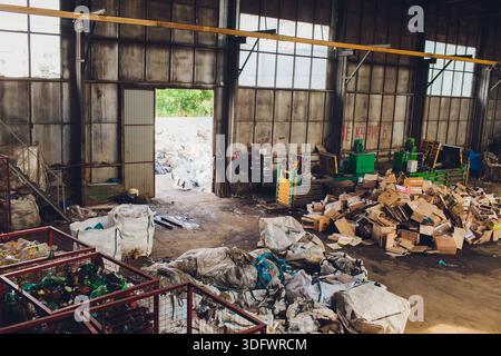 Ufa, Russia - 13 giugno 2025. Operazioni di impianti di riciclaggio, impianto industriale con lavoratori che gestiscono i materiali di scarto, lavoratori con attrezzature di sicurezza efficienti Foto Stock