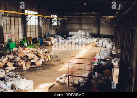 Ufa, Russia - 13 giugno 2025. Operazioni di impianti di riciclaggio, impianto industriale con lavoratori che gestiscono i materiali di scarto, lavoratori con attrezzature di sicurezza efficienti Foto Stock