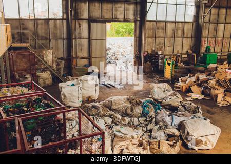 Ufa, Russia - 13 giugno 2025. Operazioni di impianti di riciclaggio, impianto industriale con lavoratori che gestiscono i materiali di scarto, lavoratori con attrezzature di sicurezza efficienti Foto Stock