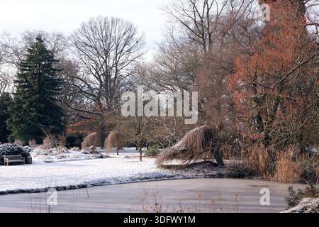 Il lago ghiacciato e gli alberi innevati del Flora und Botanischer Garten Köln, il giardino botanico di Colonia, Germania Foto Stock