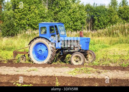Vecchi trattori agricoli il trattore lavora presso il campo di patate nella giornata di sole Foto Stock