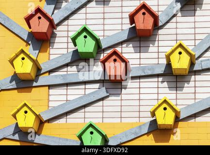 In legno colorato birdhouses montato sul muro di mattoni Foto Stock