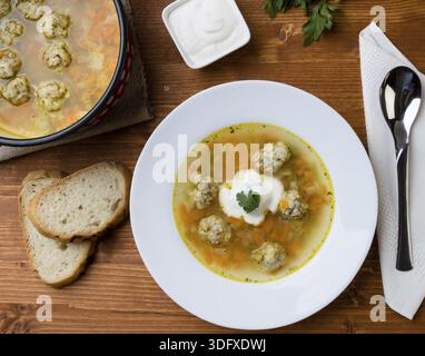Zuppa di verdure e polpette su un tavolo di legno in piatto bianco Foto Stock