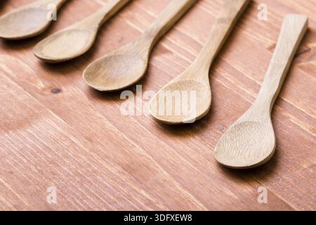 Cinque cucchiai di legno marroni su un tavolo di legno Foto Stock
