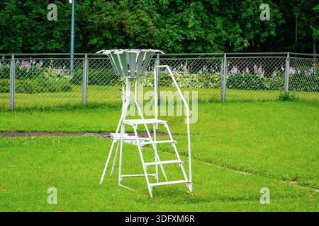 Una stazione meteorologica con un pluviometro e un termometro si trova su un sito erboso circondato da una recinzione, che funge da strumento fondamentale per i dati climatici Foto Stock