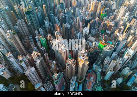 La prospettiva dall'alto verso il basso su Hong Kong rivela l'incredibile densità dei suoi alti edifici. La luce del sole scorre attraverso le torri, evidenziando la V Foto Stock