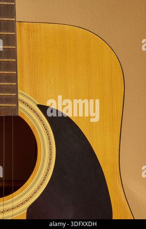 Primo piano del corpo della chitarra acustica e delle corde su sfondo beige con spazio di copia Foto Stock