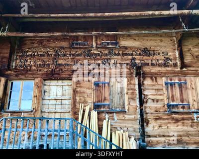 La facciata di un'antica capanna alpina svizzera presenta legno scuro e intemprato, tradizionali persiane alle finestre e robuste ringhiere in legno, l'Oberland Bernese Foto Stock