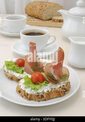 Colazione con una tazza di caffè e un panino di pane integrale con ricotta e prosciutto Foto Stock