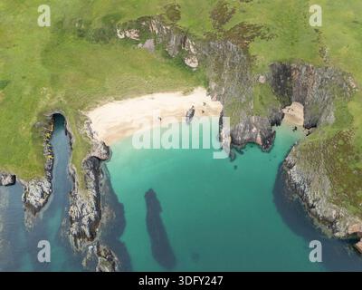 Veduta aerea della costa rocciosa frastagliata, delle spiagge e delle grotte marine sull'isola disabitata di Neave (o Coomb Island), Sutherland, Scozia, Regno Unito, luglio 2025 Foto Stock