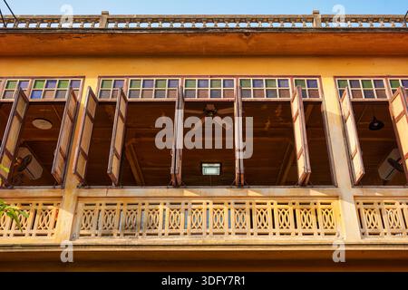 Architettura storica tradizionale con finestre in legno, tapparella, ventilatore a soffitto e ringhiera decorativa del balcone. Facciata esterna in legno di stile cinese Foto Stock