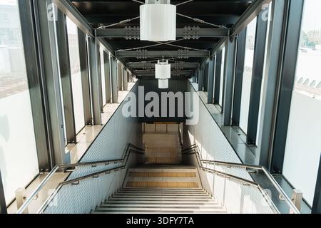 Prospettiva d'ingresso di scale simmetriche che scendono nel moderno edificio della stazione della metropolitana Foto Stock