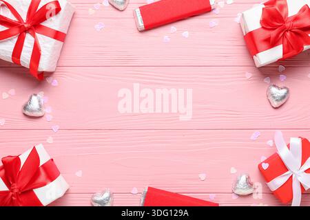 Telaio realizzato in scatole regalo con caramelle su sfondo in legno rosa. Festa di San Valentino Foto Stock