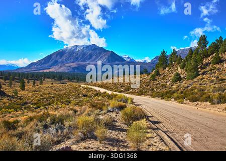Dirt Road e Snow Capped Mountain sotto Blue Sky Eastern Sierra California Foto Stock