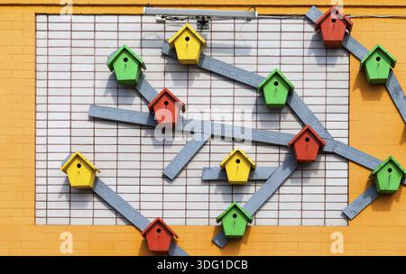 In legno colorato birdhouses montato sul muro di mattoni Foto Stock