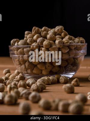 Asciugare i ceci marroni in un recipiente di vetro su un tavolo di legno Foto Stock