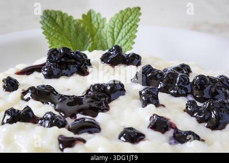 Budino di riso fatto in casa con crema di mirtilli su piatto bianco Foto Stock