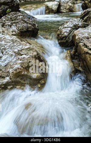 Fiume di montagna fresco e infuriato che scorre tra le rocce Foto Stock