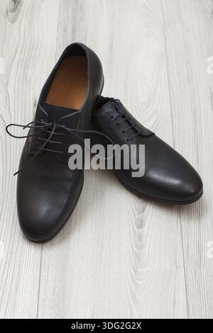 Coppia di cuoio nero scarpe uomo in grigio sullo sfondo di legno. Elegante e le scarpe eleganti per uomini Foto Stock
