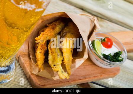 Acciughe fritte in padella con salsa cremosa al formaggio, verdure Foto Stock
