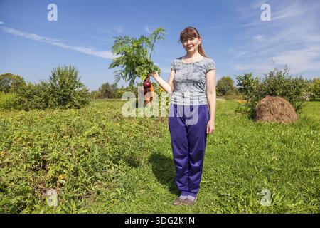 Giovane donna tenendo un covone di verdura in mano Foto Stock