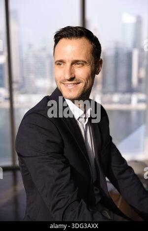 Bell'uomo d'affari latino che guarda lontano con un sorriso da sogno Foto Stock