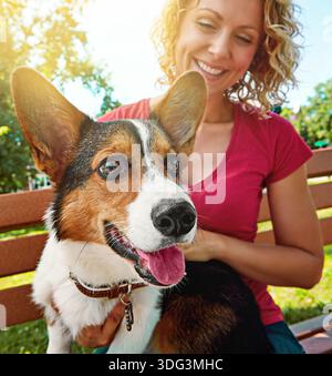 Donna felice, panchina e giocare con il cane nel parco per legare, amare gli animali o prendersi cura della natura. Donna, canina o proprietaria di animali con sorriso o bagliore per Foto Stock