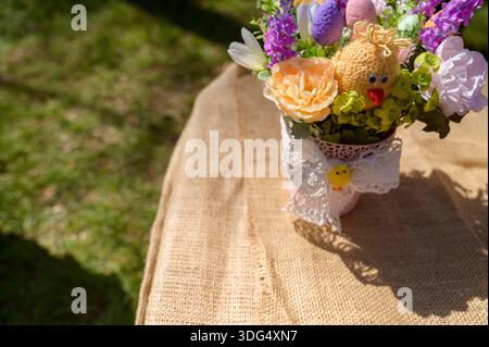 Le feste primaverili sono caratterizzate da un pulcino a uncinetto e lavanda viola in un vaso decorativo. Concetto di ornamenti pasquali artigianali, arredamento per vivai, Foto Stock