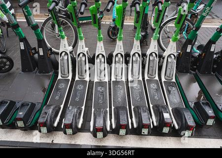 Fila di scooter elettrici parcheggiati sulla strada cittadina Foto Stock