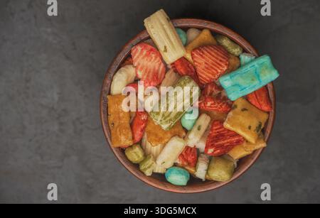 Primo piano di cracker di riso giapponesi in una ciotola con sfondo isolato. Cracker di riso colorati assortiti su sfondo nero. Spuntini per feste. Foto Stock