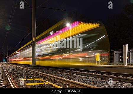 Lunga esposizione dinamica di un tram in rapido movimento con sentieri luminosi colorati di notte a Utrecht, Paesi Bassi. Foto Stock