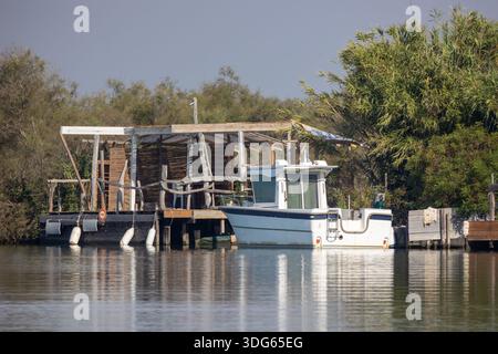 Piccola barca ormeggiata vicino a una cabina in riva all'acqua Foto Stock